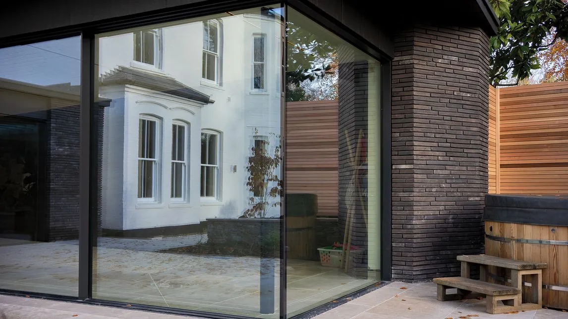 Frameless glazed corner of the extension looking back to the period house