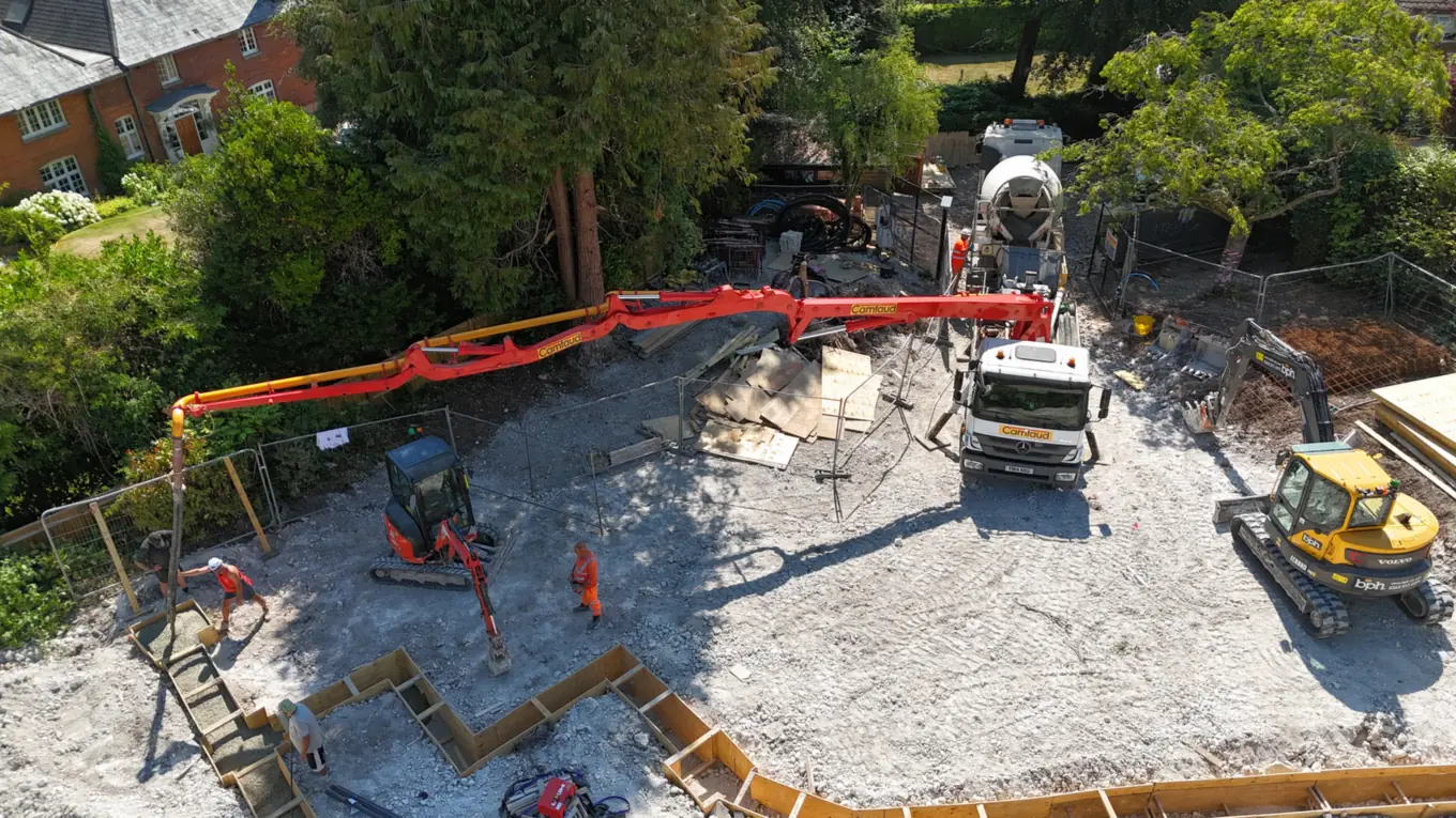 Strip foundations being poured, with the concrete pump boom over the site