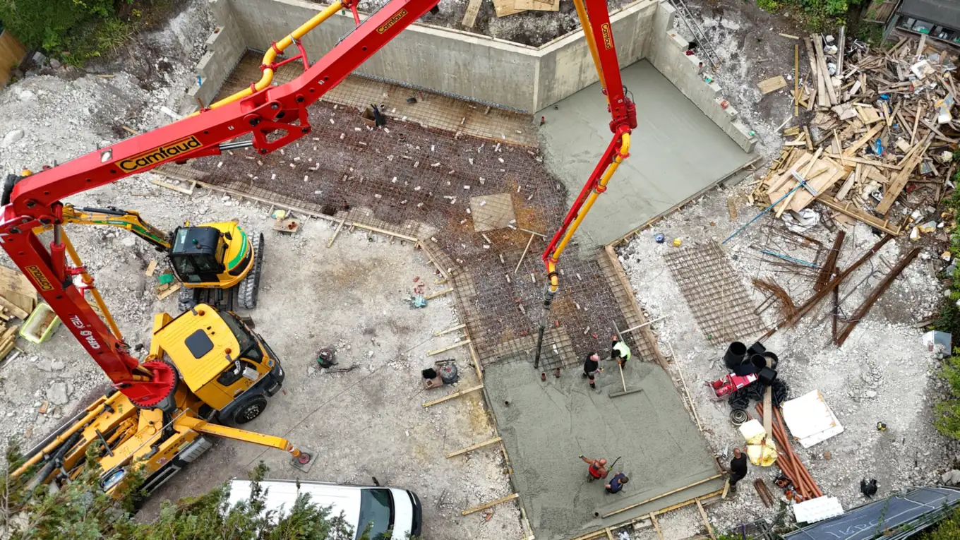 Aerial view of the ground floor slab being poured between the retaining walls